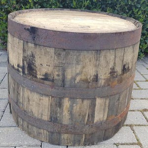 May include: A rustic wooden barrel with metal hoops. The barrel is made of aged wood with a flat top and bottom. The metal bands are rusty. The barrel is likely used for storage or decorative purposes.