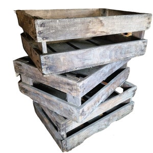 May include: A stack of four wooden crates, weathered and worn with age. The crates are stacked in a staggered pattern, creating a rustic and vintage aesthetic.
