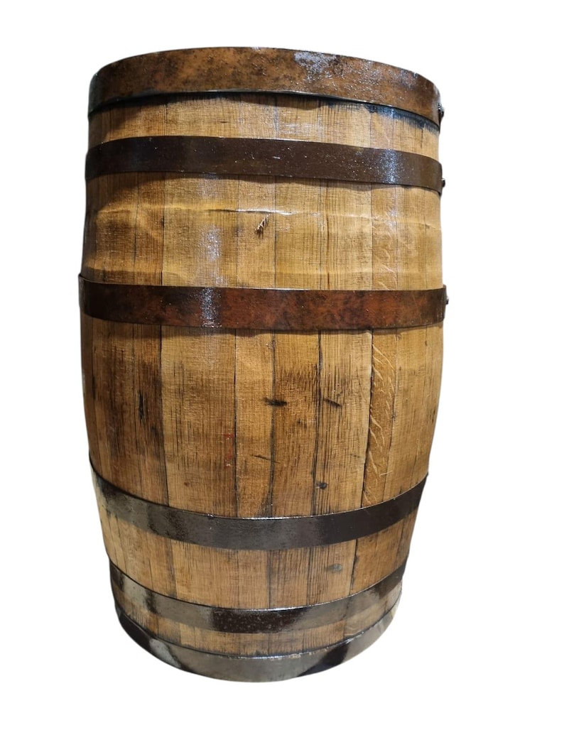 May include: A wooden barrel with a light brown finish, held together by dark metal bands. The barrel has a slightly weathered appearance, suggesting it may have been used for aging or storage. The wood grain is visible.