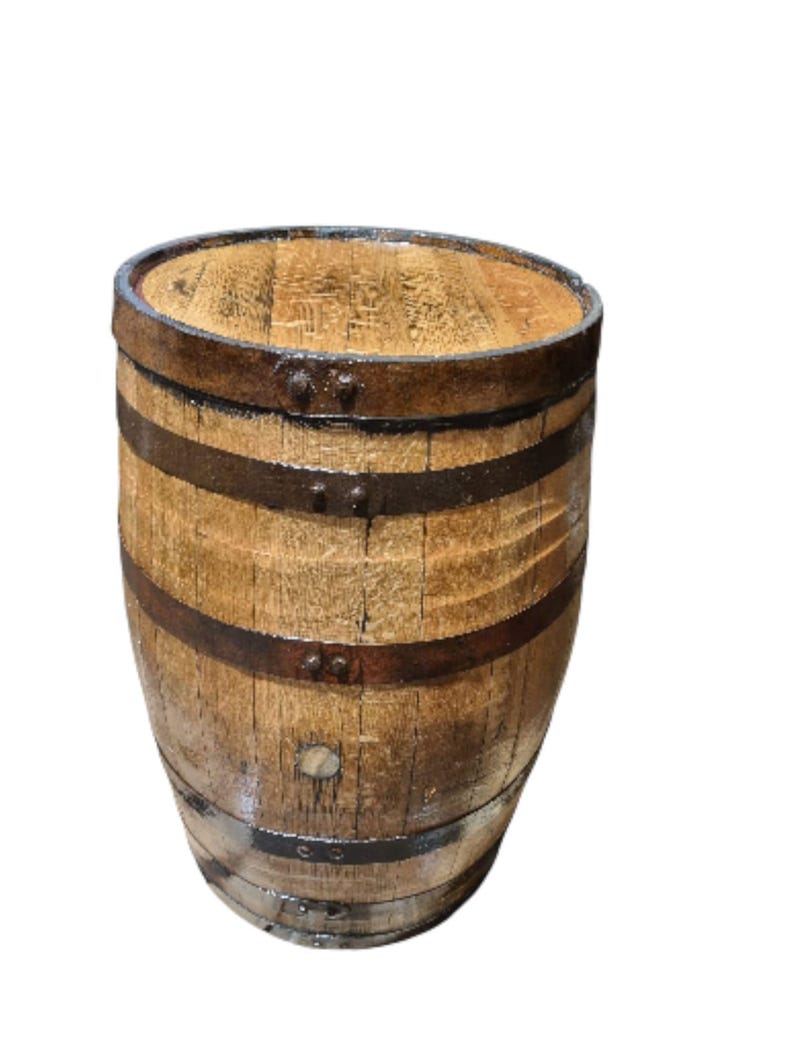 May include: A wooden barrel with a light brown finish and dark metal bands. The barrel has a rounded top and is made of wooden planks. The metal bands are secured with rivets. The barrel is likely used for storage or decoration.
