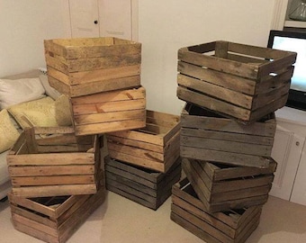 May include: A stack of wooden crates, some are stacked on top of each other, some are on the floor. The crates are made of natural wood and have a rustic look.