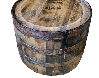Op de afbeelding: Een verweerde houten vat met metalen banden. De bovenkant van het vat heeft de tekst "BEAM BRANDS U.S. BOURBON WHISKEY" en "B18C12 TANK 224" erop gedrukt. Het vat is bruin met donkere accenten.