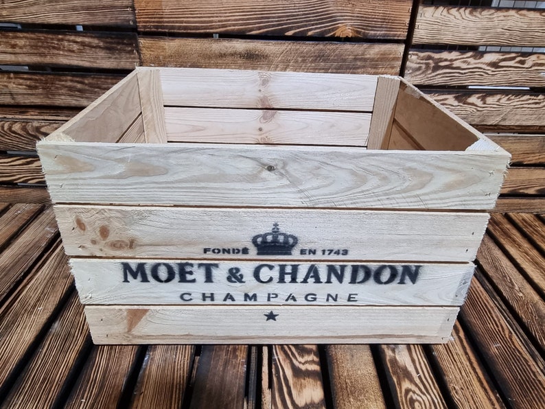 以下が含まれることがあります： 前面に「FONDE EN 1743 MOET & CHANDON CHAMPAGNE」と印刷された木製の箱。テキストの上に王冠があります。