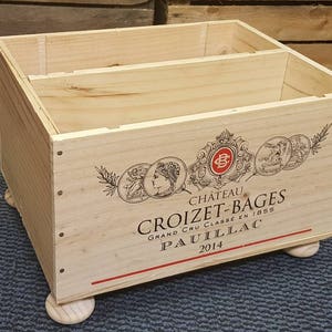 Può includere: Cassa di legno per vino con un'etichetta che recita "Chateau Croizet-Bages Grand Cru Classe en 1855 Pauillac 2014". La cassa ha quattro gambe di legno.