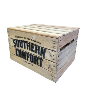 Pode incluir: Uma caixa de madeira com as palavras "SOUTHERN COMFORT" e "EST. 1874" impressas em preto. A caixa tamb&eacute;m tem o texto "THE SPIRIT OF NEW ORLEANS" impresso. A caixa &eacute; feita de madeira clara.