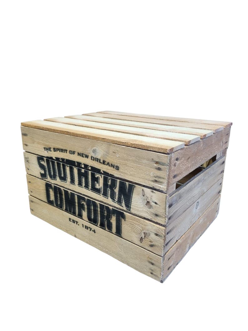 Pode incluir: Uma caixa de madeira com as palavras "SOUTHERN COMFORT" e "EST. 1874" impressas em preto. A caixa tamb&eacute;m tem o texto "THE SPIRIT OF NEW ORLEANS" impresso. A caixa &eacute; feita de madeira clara.
