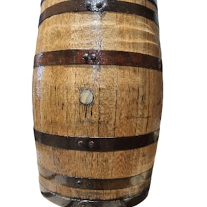 May include: A wooden barrel with dark metal bands. The barrel has a light brown color with visible wood grain and is held together by several dark metal bands. The barrel is likely used for storage or decoration.