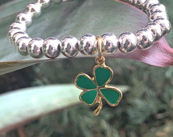 Pulsera con dije de trébol de cuatro hojas: esmalte verde bañado en oro y cuentas de plata.