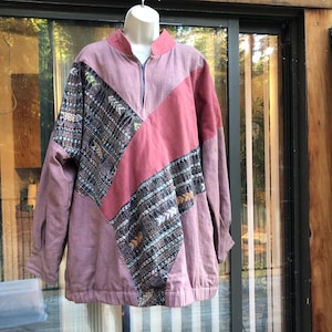 May include: A mauve, pink, and brown patchwork jacket with a zipper closure. The jacket has a collar and long sleeves.