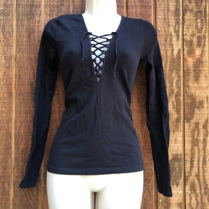 May include: Black long-sleeved shirt with a lace-up detail at the neckline.