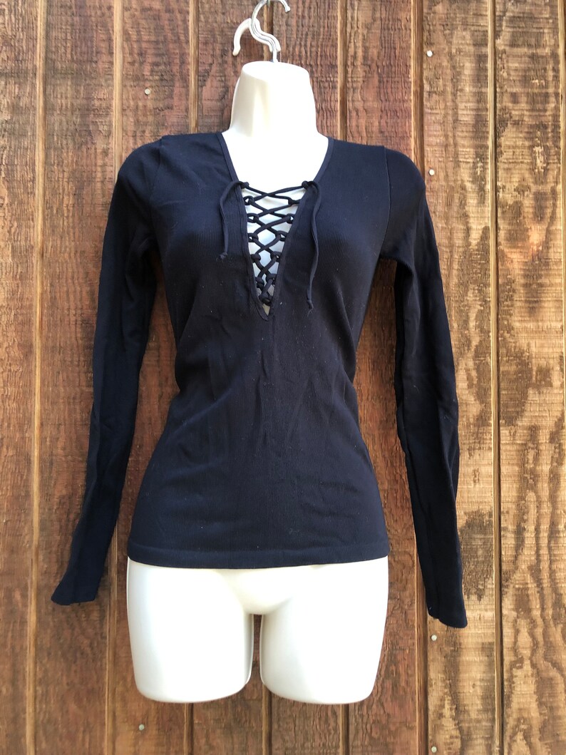 May include: Black long-sleeved shirt with a lace-up detail at the neckline.