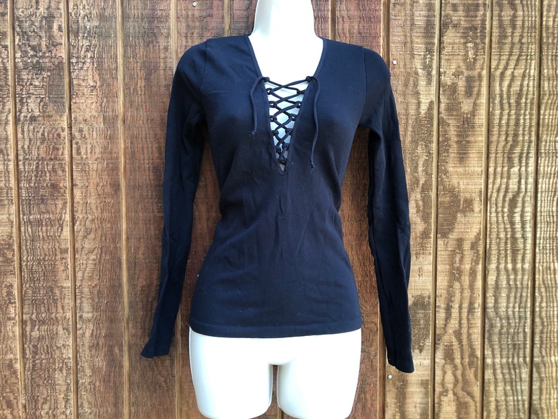 May include: A black long-sleeved shirt with a lace-up neckline. The shirt is fitted and has a v-neck.