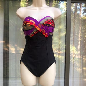 May include: A strapless swimsuit with a black bottom and a colorful patterned top. The top is made of a purple, orange, and gray fabric with a floral design.