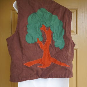 May include: A brown vest with a green and orange tree applique on the back.