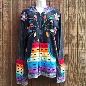 May include: Black hooded sweatshirt with a rainbow striped pocket and colorful floral embroidery.