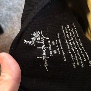 May include: Black ribbed tank top with a white "free people" logo and care instructions. The tag says "92% nylon 8% spandex, elasthane, machine wash cold gentle cycle, non-chlorine bleach, lay flat to dry, wash separately by hand, do not iron, tumble dry low."