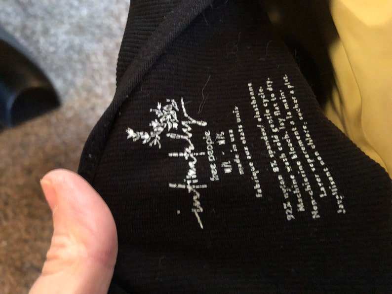 May include: Black ribbed tank top with a white "free people" logo and care instructions. The tag says "92% nylon 8% spandex, elasthane, machine wash cold gentle cycle, non-chlorine bleach, lay flat to dry, wash separately by hand, do not iron, tumble dry low."
