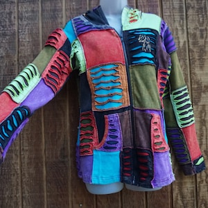 May include: A patchwork hoodie with a full zipper, featuring a variety of colors including red, purple, green, and blue. The jacket has distressed details and a hood. The sleeves have cut-out designs.