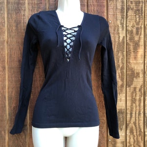 May include: Black long-sleeved shirt with a lace-up V-neck.