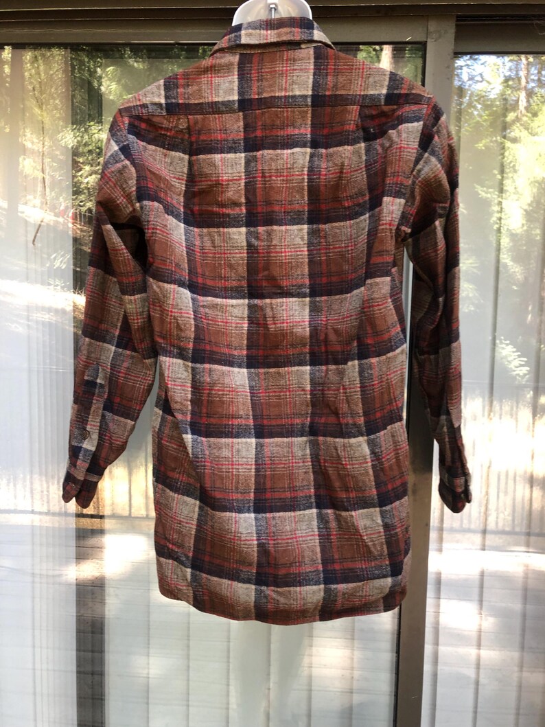 May include: A long-sleeved plaid shirt in shades of brown, red, and navy blue. The shirt features a classic button-down design with a collared neckline and cuffs. The plaid pattern is a traditional design.