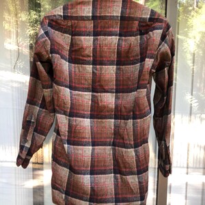 May include: A long-sleeved plaid shirt in shades of brown, red, and navy blue. The shirt is hanging on a white hanger, showcasing the back of the garment. The plaid pattern is a classic design, suitable for casual wear.