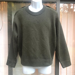 May include: Olive green crew neck sweater with shoulder patches. The long-sleeved sweater is displayed on a white mannequin. The sweater has a textured knit pattern and a ribbed hem and cuffs.