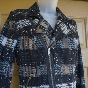 May include: A patterned jacket with a diagonal zipper and a notched collar. The jacket features a mix of colors including black, white, brown, and teal. The jacket has a classic biker style with a modern twist.