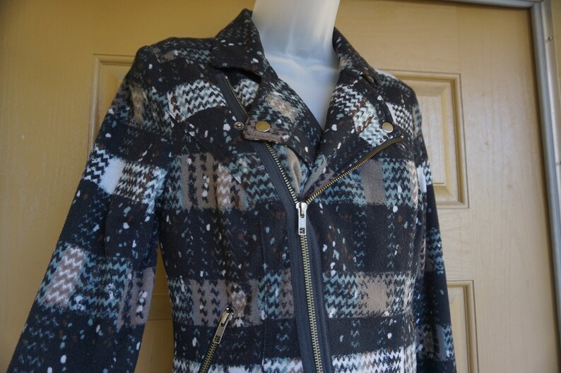 May include: A patterned jacket with a diagonal zipper and a notched collar. The jacket features a mix of colors including black, white, brown, and teal. The jacket has a classic biker style with a modern twist.