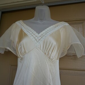 May include: A vintage ivory slip dress with sheer, ruffled sleeves and a lace trim around the neckline.