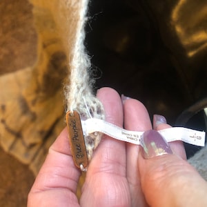 May include: A close-up of a white Free People sweater with a brown tag that says "Free People" and a white tag that says "Made in China".