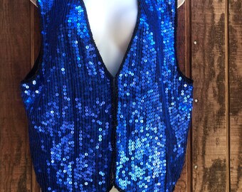 May include: A blue sequined vest with a V-neck and a pointed hem.