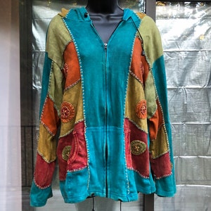 May include: A teal blue patchwork hoodie with a zipper closure. The hoodie is made of different colored fabrics, including orange, brown, and green. The fabric is stitched together with decorative stitching. The hoodie has a hood and a pocket on each side.