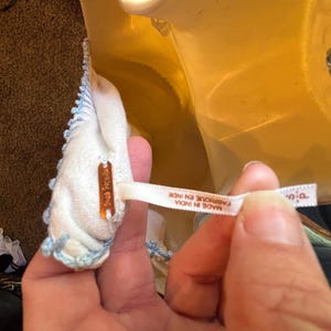 May include: A close-up of a white garment with light blue trim. The garment has a tag that reads "Free People". A white ribbon tag reads "MADE IN INDIA FABRIQUE EN INDE".