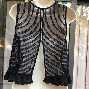 May include: Black sleeveless lace top with a button down back and a ruffled hem.