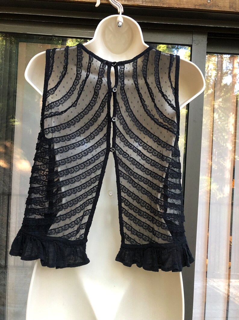 May include: Black sleeveless lace top with a button down back and a ruffled hem.