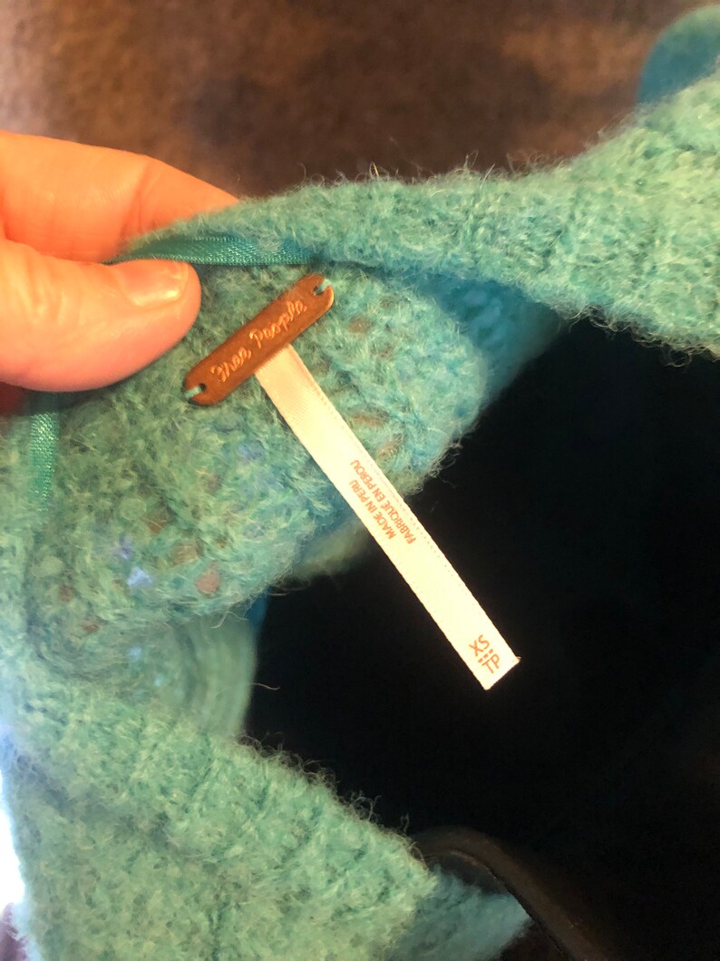 May include: A teal blue fuzzy sweater with a Free People tag and a size tag that says "Size X-S" and "Made in Peru".