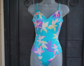 May include: A turquoise swimsuit with a tropical floral print in pink, yellow, and purple.
