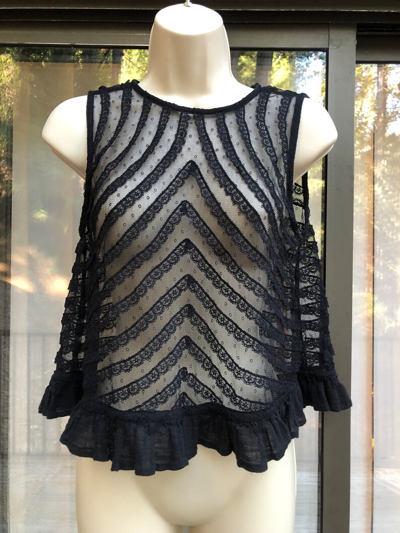 May include: Black lace sleeveless top with a chevron pattern and a ruffled hem.
