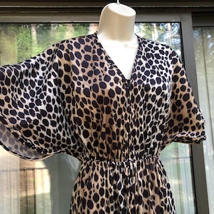 May include: A brown and black leopard print dress with a V-neck and short sleeves. The dress has a cinched waist and a flowing skirt.