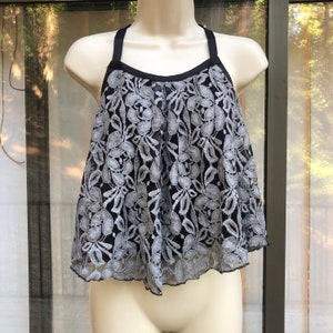 May include: A black and gray lace top with a halter neckline and a ruffled hem.