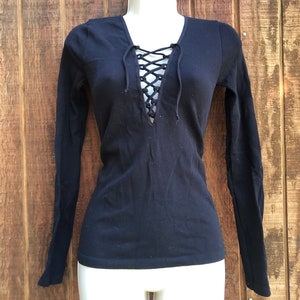 May include: Black long-sleeved shirt with a lace-up V-neck.