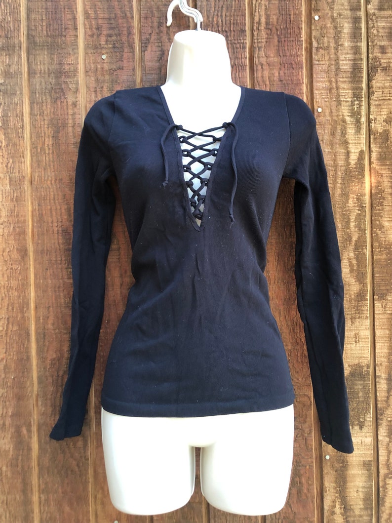 May include: Black long-sleeved shirt with a lace-up V-neck.