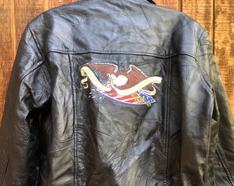 May include: Black leather jacket with a quilted design and an embroidered eagle patch on the back. The eagle is holding a banner with the words "United We Stand".