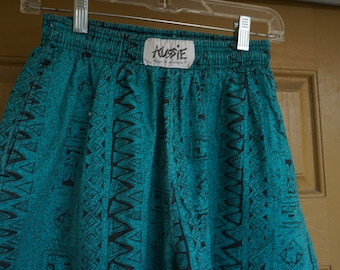 May include: Teal and black patterned shorts with an elastic waistband. The shorts have a repeating geometric design. The tag reads "AUSSIE" in white letters on a white background.