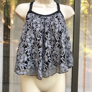 May include: A black and silver lace top with a halter neckline and a ruffled hem.