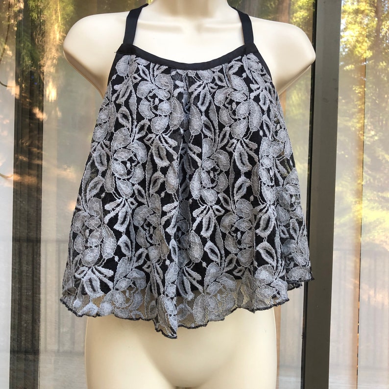 May include: A black and silver lace top with a halter neckline and a ruffled hem.