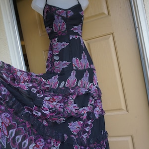 May include: Black halter dress with a tiered skirt. The dress features a paisley pattern in shades of purple and pink. The dress has a flowing, bohemian style.