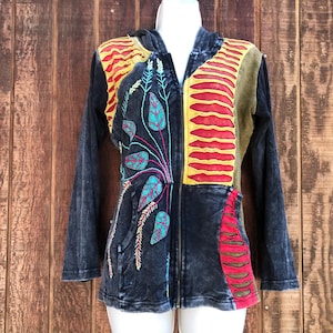 May include: A black hooded jacket with a zipper closure and colorful embroidered floral designs. The jacket has a patchwork design with red, yellow, and green fabric.