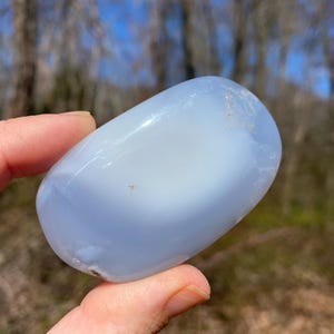 May include: A smooth, light blue, oval-shaped, polished blue lace agate stone.