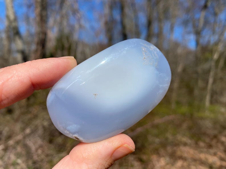 May include: A smooth, light blue, oval-shaped, polished blue lace agate stone.